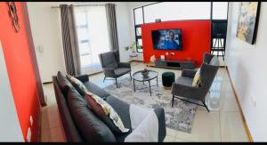 a living room with a couch and chairs and a tv at Palm Villa GuestHouse in Jwaneng