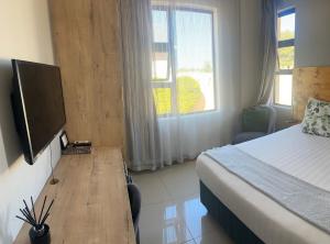 a bedroom with a bed and a desk with a television at Palm Villa GuestHouse in Jwaneng +10 photos
