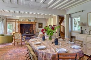 a dining room with a table and a fireplace at La maison du fermier in Saint-Wandrille-Rançon