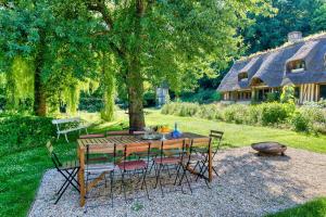 a wooden table and chairs in a yard with a house at La maison du fermier in Saint-Wandrille-Rançon
