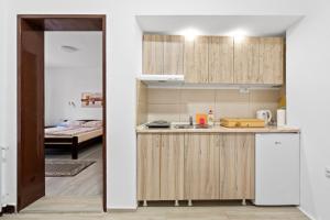 a kitchen with wooden cabinets and a room with a bed at Apartmani Sokobanja Alexandar in Soko Banja
