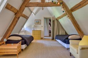 a attic bedroom with two beds and a chair at La maison du fermier in Saint-Wandrille-Rançon