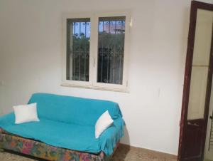 a blue couch in a room with two windows at La casa di Anna Maria in Nardò