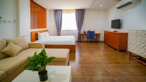 杜科姆Express City Hotel - Duqm的一间带沙发、床和电视的酒店房间