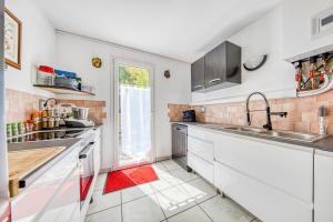 una cucina con mobili bianchi e una grande finestra di Maison de l’océan - Hourtin, Médoc a Hourtin