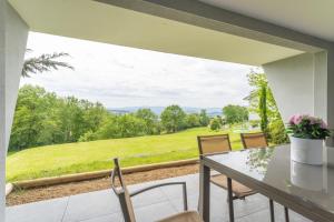 a balcony with a table and chairs and a view at Le Petit Bois évasion nature entre Genève&Annecy in Copponex +12 photos