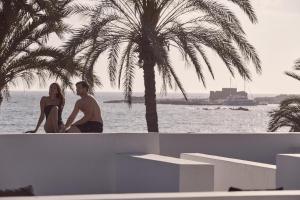 un uomo e una donna seduti su un muro vicino all'oceano di Almyra a Paphos Altre 37 foto