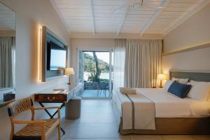 a bedroom with a bed and a desk and a television at Makryammos in Limenas