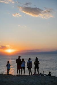 a group of people standing on the beach watching the sunset at Makryammos in Limenas