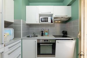 a kitchen with white cabinets and a sink and a microwave at L'estivalière in Golfe-Juan +11 photos