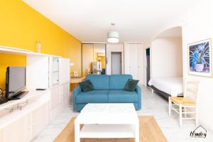 a living room with a blue couch and a tv at L'estivalière in Golfe-Juan