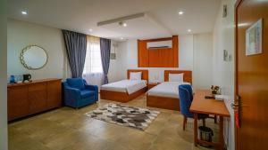 杜科姆Express City Hotel - Duqm的一间有两张床和一把蓝色椅子的酒店房间 更多37张照片