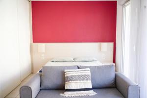 a bedroom with a bed and a couch with a red wall at Studio climatisé à Divonne-les-Bains in Divonne-les-Bains