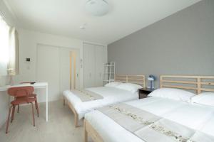 a bedroom with two beds and a desk and a chair at GuesthouseA in Osaka