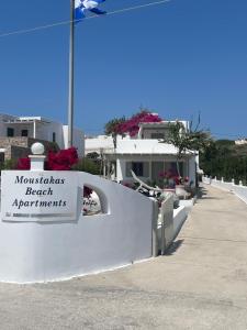 a white fence with a sign that reads mousias beach apartments at Moustakas Beach Apartments in Adamantas