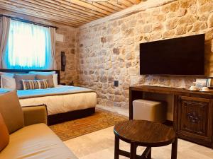 a bedroom with a bed and a tv on a stone wall at Cybele in Cappadocia in Uçhisar