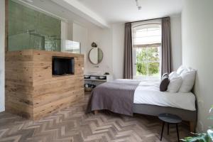 a bedroom with a bed and a television and a window at Boutique Hotel De Witte Dame in Abcoude