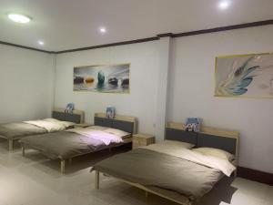 3 camas en una habitación con pinturas en la pared en FUBON World, en Vientiane
