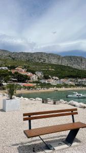 a wooden bench sitting on a beach near the water at Superior Apartman Vujević, Duće in Duće +12 photos