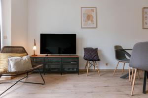 a living room with a flat screen tv and chairs at Huswell - Bright & Stylish Apartment with Balcony in Knokke-Heist