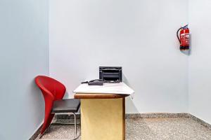 a red chair and a desk with a computer on it at HOTEL O THE ROYAL INN in Jaipur