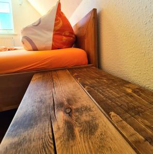 Una cama con una almohada naranja y una mesa de madera. en Ferienwohnung Seemöwe Usedom, en Heringsdorf
