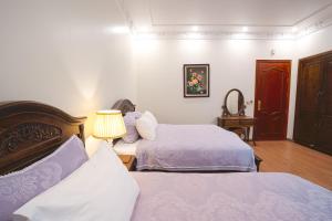 a hotel room with two beds and a lamp at Pearl Hotel Ha Long in Ha Long