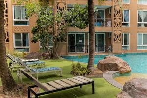 ein Pool mit Bänken und ein Gebäude in der Unterkunft Atlantis Condo Resort Pattaya in Jomtien Beach