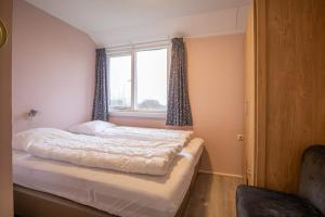 a bedroom with a bed and a window with curtains at Nieuwlanderweg 63 in De Waal