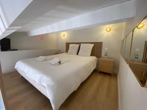 a bedroom with a large white bed with a heart on the wall at Village naturiste Appart B Port Soleil in Cap d'Agde +11 photos