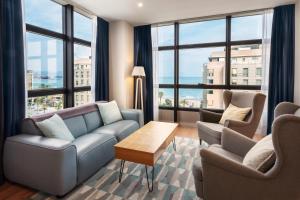 a living room with a couch and chairs and windows at Catalonia Málaga in Málaga