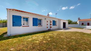 Casa blanca con ventanas azules y patio en Oceana de l Isle de Riez, en Saint-Hilaire-de-Riez