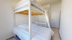 Un dormitorio con dos literas con sábanas blancas. en Oceana de l Isle de Riez, en Saint-Hilaire-de-Riez