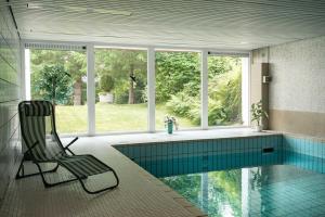 a swimming pool with a chair in a house at Apartment Schwarzwald mit Zugang Pool und Sauna in Schönwald