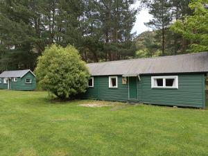 a green building with a tree in a yard at Danseys Pass Holiday Park in Oamaru