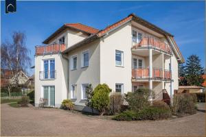 Una casa blanca con balcones en un lateral. en Ferienwohnung Pretzer, en Ostseebad Koserow
