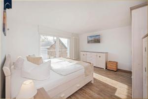 a white bedroom with a bed and a window at Ferienwohnung Haffblick in Kamminke