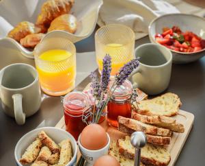 a table with a breakfast of toast and eggs and juice at Les Gîtes de Laure - L'Eden Romantique, B&B, Spa privatif et Petit Déjeuner, Couloir de nage, 10mn Carcassonne in Malves