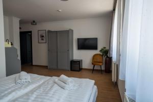 a bedroom with a white bed and a television at Prémium Panzió Miskolctapolca in Miskolctapolca