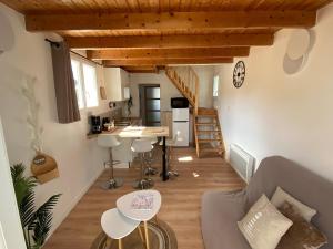 a living room with a couch and a kitchen and stairs at Tiny house proche de la Plage in Plougonvelin