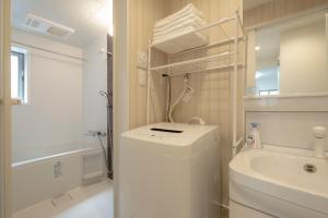 a white bathroom with a sink and a washing machine at GuesthouseA in Osaka