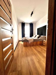 a bedroom with a bed and a wooden floor at Apartament Poznańska 1 in Suwałki