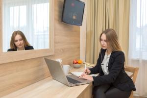 une femme assise à une table avec un ordinateur portable dans l'établissement Dozamel, à Kołobrzeg