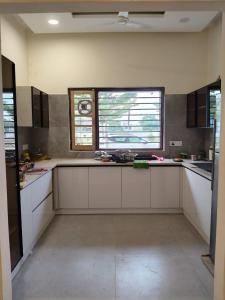 a large kitchen with white cabinets and two windows at Park Avenue in Ludhiana