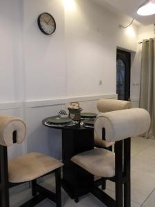 a room with a table and two chairs and a clock at Maison meublé Bonamoussadi 2 chambres in Kofa +8 photos