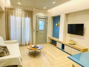 a living room with a couch and a table and a tv at Modern Apartment, Few Meters from the Beach in Néa Koróni