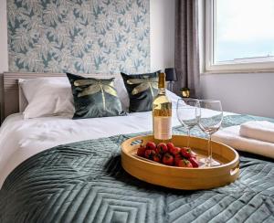 a tray of strawberries and a bottle of wine and glasses on a bed at Luxury in City -14- Stylish Free Parking in Łódź