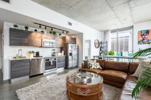 a living room with a brown couch and a kitchen at 2BR Centro Condo - Gym Pool & City Views in Miami