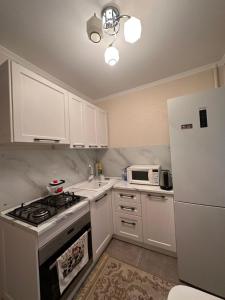 a kitchen with white cabinets and a stove and a refrigerator at Квартира в районе Esentai Mall in Almaty