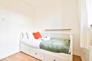 une chambre blanche avec un lit avec des draps blancs et des oreillers orange dans l'établissement Homely 5 Bed House - 15 Mins to Cardiff City, à Cardiff